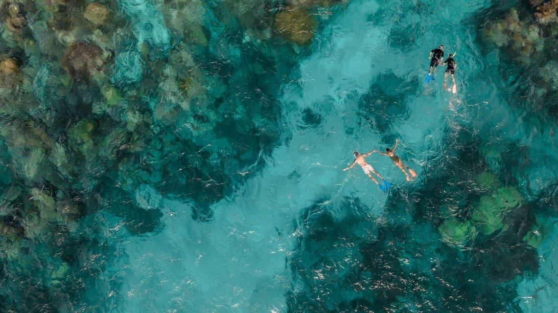 Two people snorkeling in clear water with coral reefs