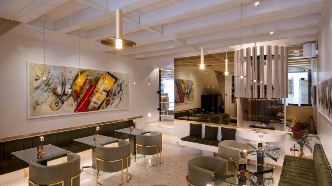 Contemporary cafe interior with glass tables, olive green chairs, abstract art on walls, and modern lighting. The atmosphere is stylish and inviting.
