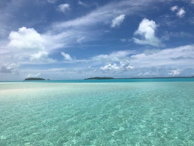 Clear blue tropical ocean water with a sand bar in the background