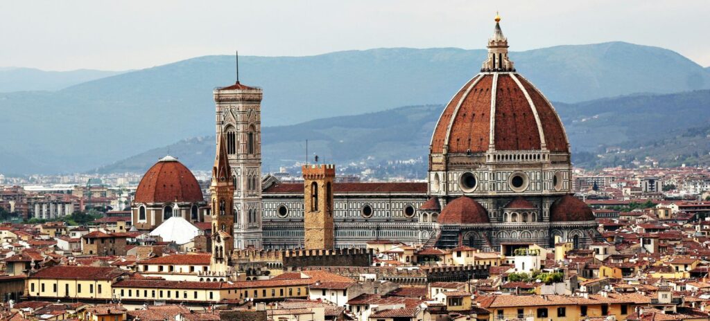 Panoramic view of Florence's skyline featuring the iconic Florence Cathedral with its large dome, surrounded by historic buildings and distant hills.