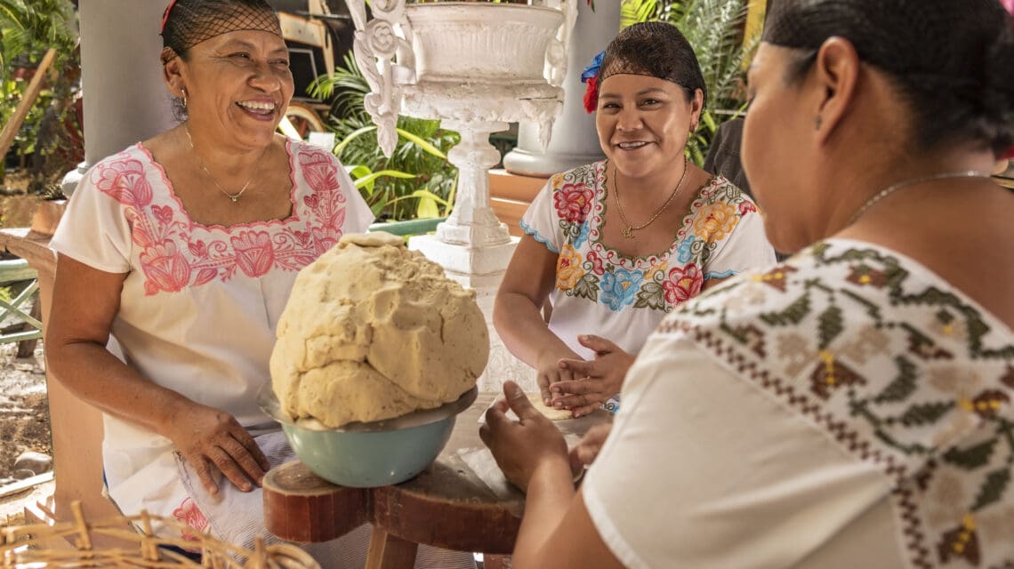 Group of smiling cooks preparing flat bread tortillas in Yucatan, Mexico