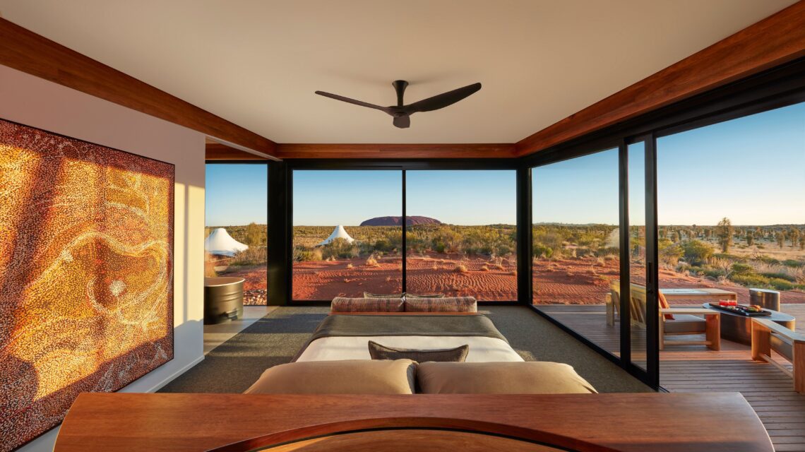 View of large red plateaued rock in the distance from luxurious bedroom with glass walls