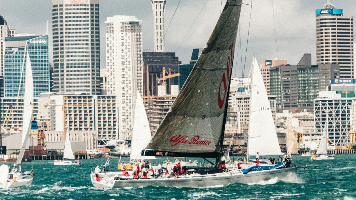 Sail boat crusing through the water with city skyline in the background
