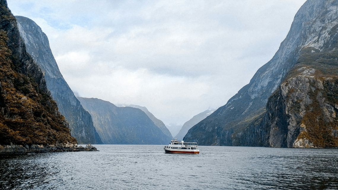 Small cruise boat in a fiord surrounded by rugged mountains