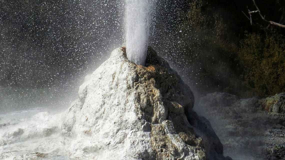 Geothermal geyser erupting with hot water and minerals