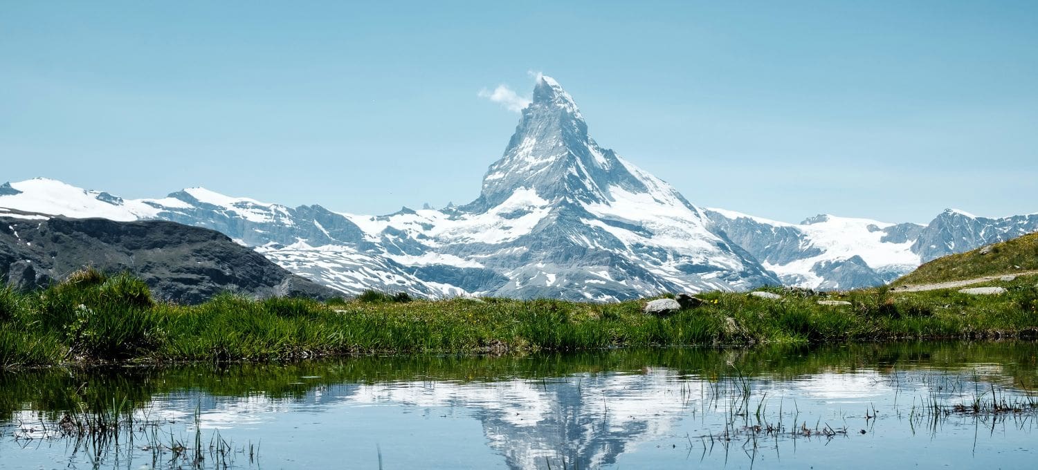 Jagged snow capped mountain range reflecting in a clear lake