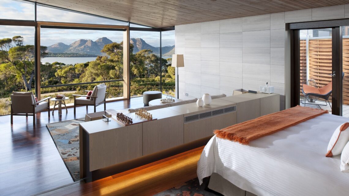Luxurious bedroom with large windows offering a scenic view of mountains and greenery. Elegant decor, cozy seating, and a calm, relaxing ambiance.