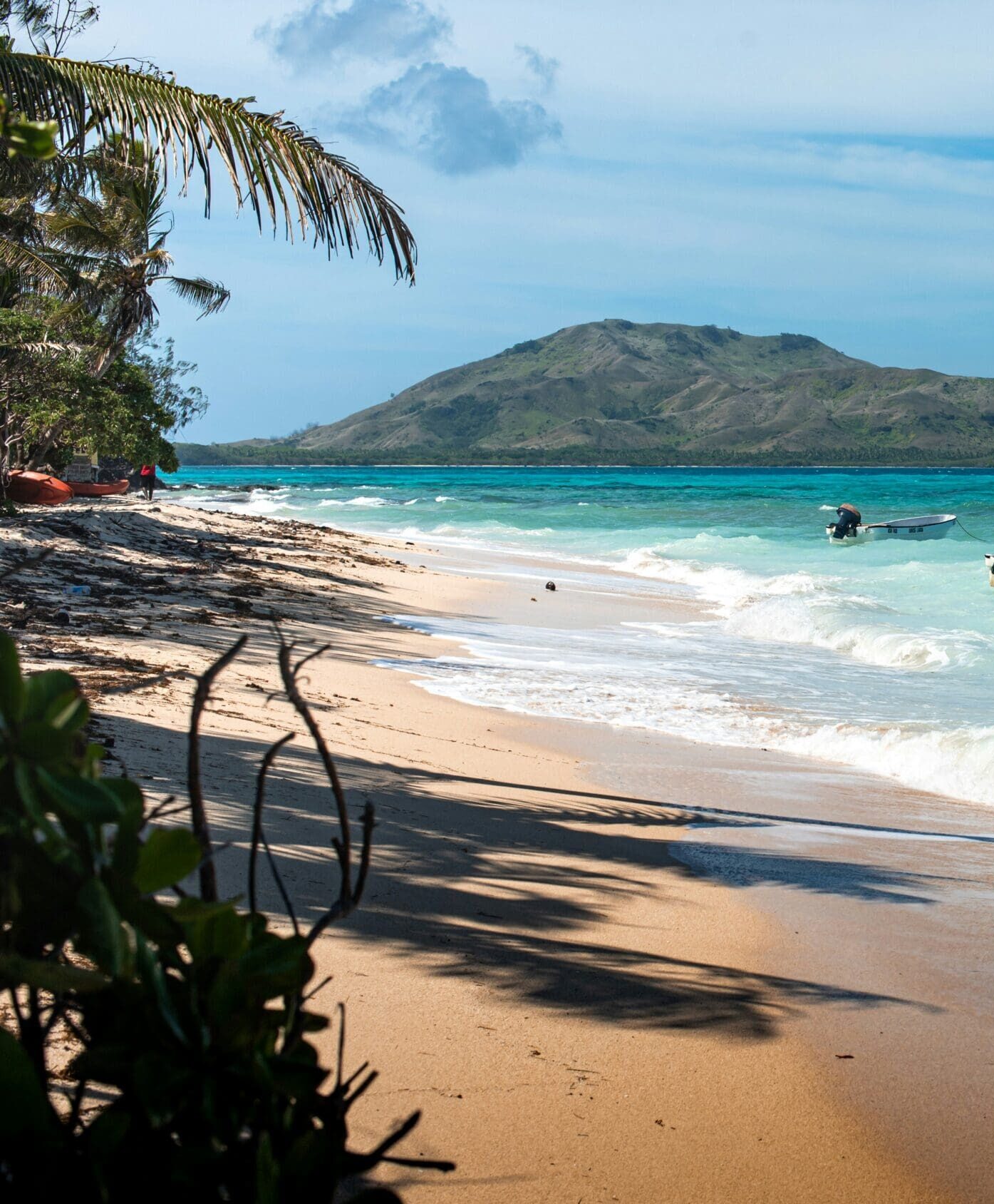 a tropical beach with a boat in the clearn ocean water