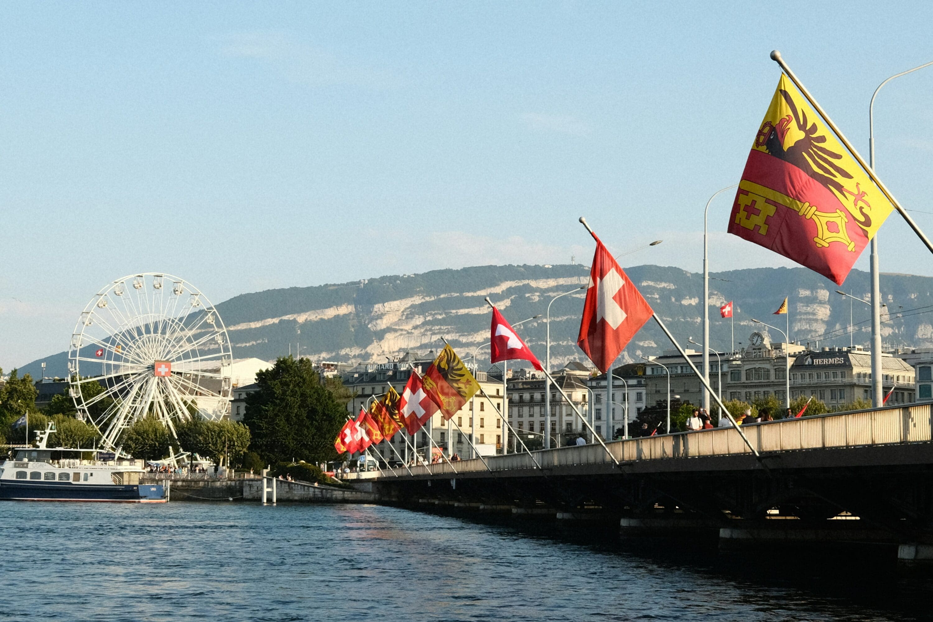 Bridge over water with flags and mountain in the background