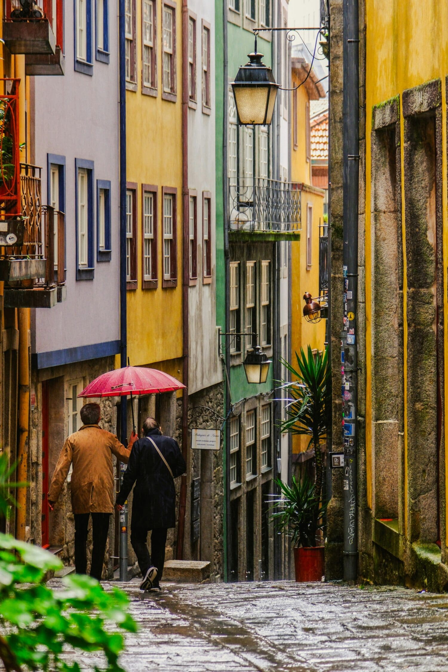 a couple of people walking down a street holding umbrellas