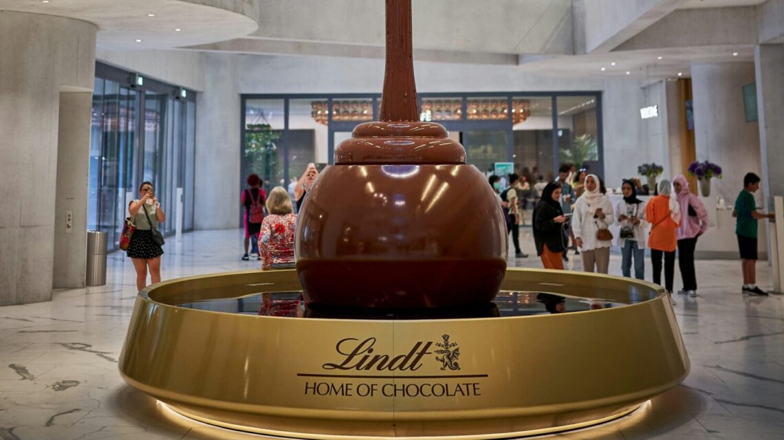 a large red and gold statue in a large building with people