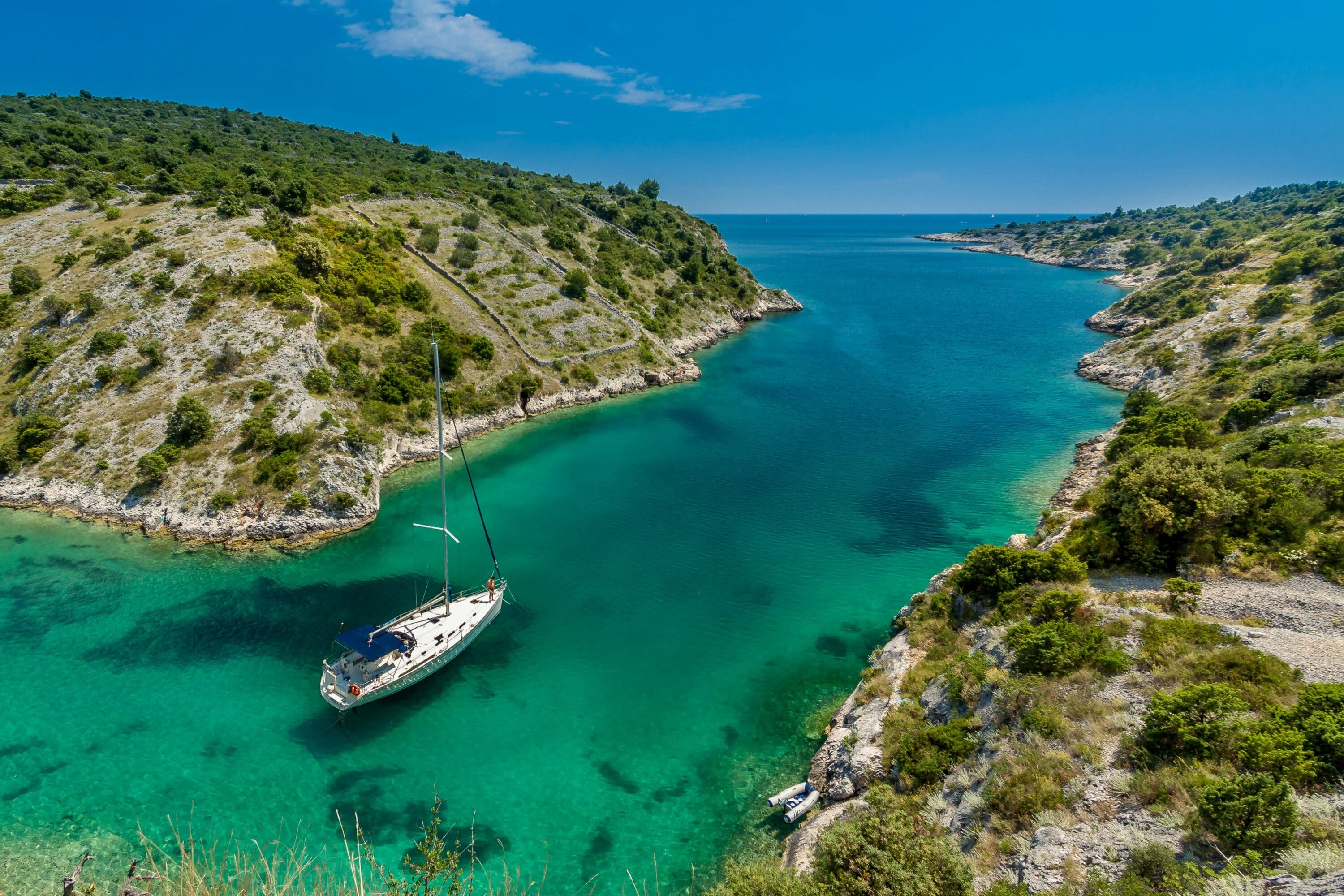 aerial-photography-of-white boat near body of water between green mountain during daytime