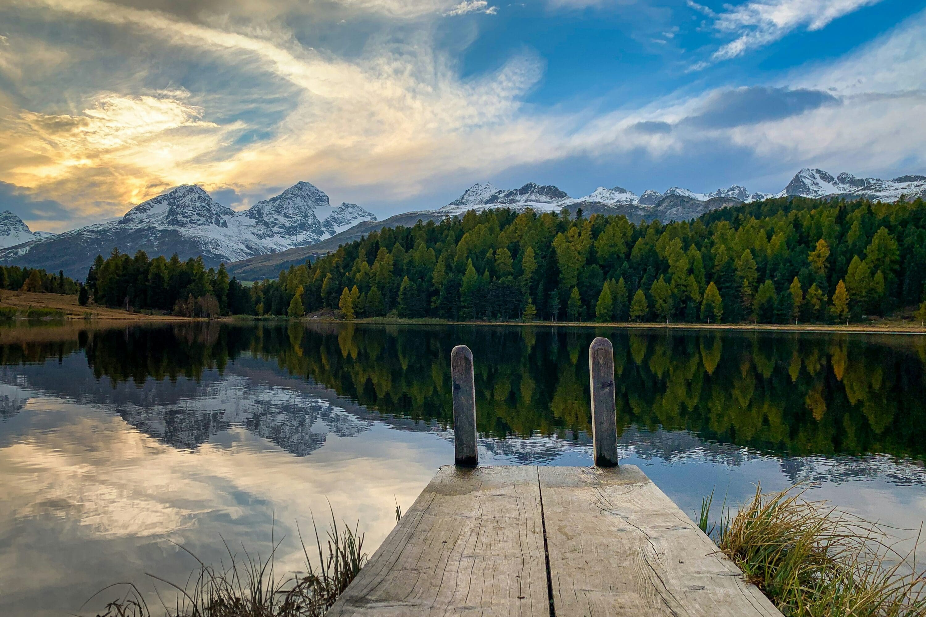 brown-wooden-dock-on-lake near green trees under white clouds and blue sky during daytime