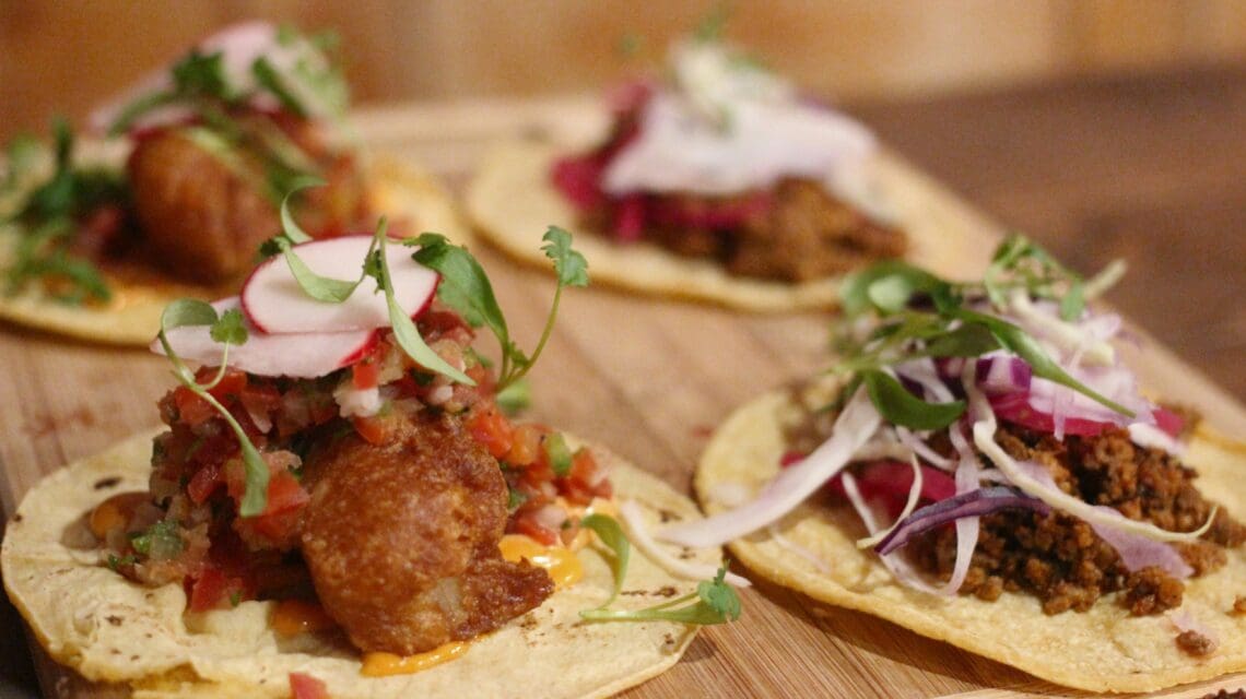 Wooden board with multiple tacos on top