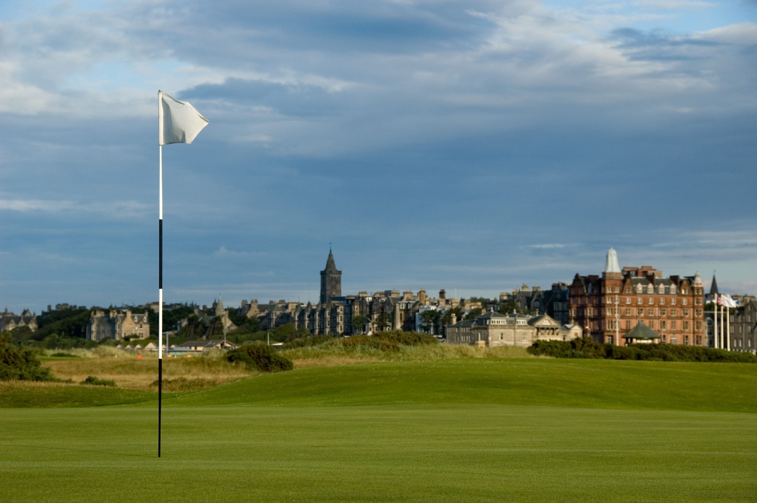 A flag on a green on one of the St Andrews golf courses. Royal and Ancient clubhouse in the background.