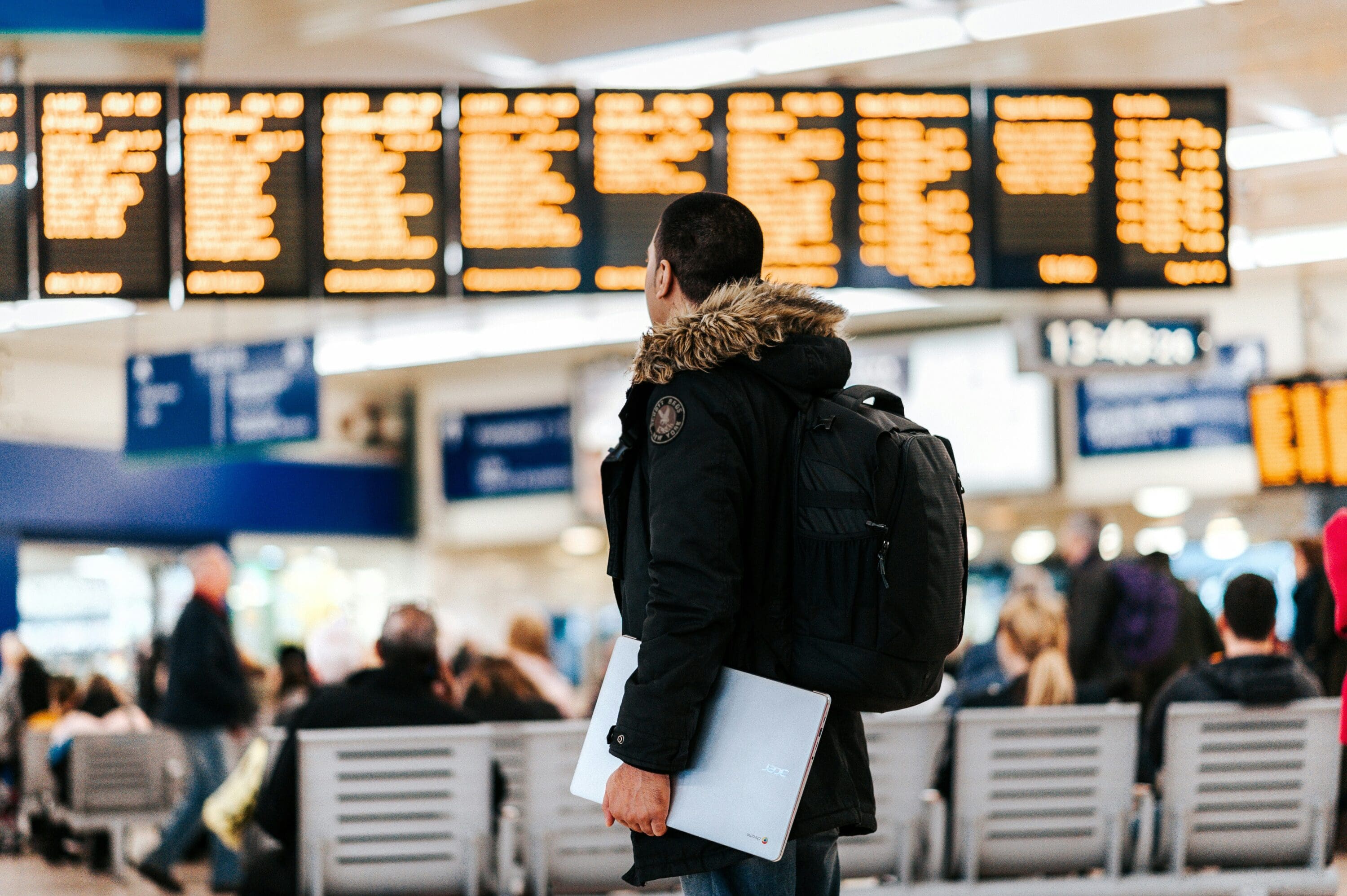 man in airport walking by electronic signboard of cancelled flights
